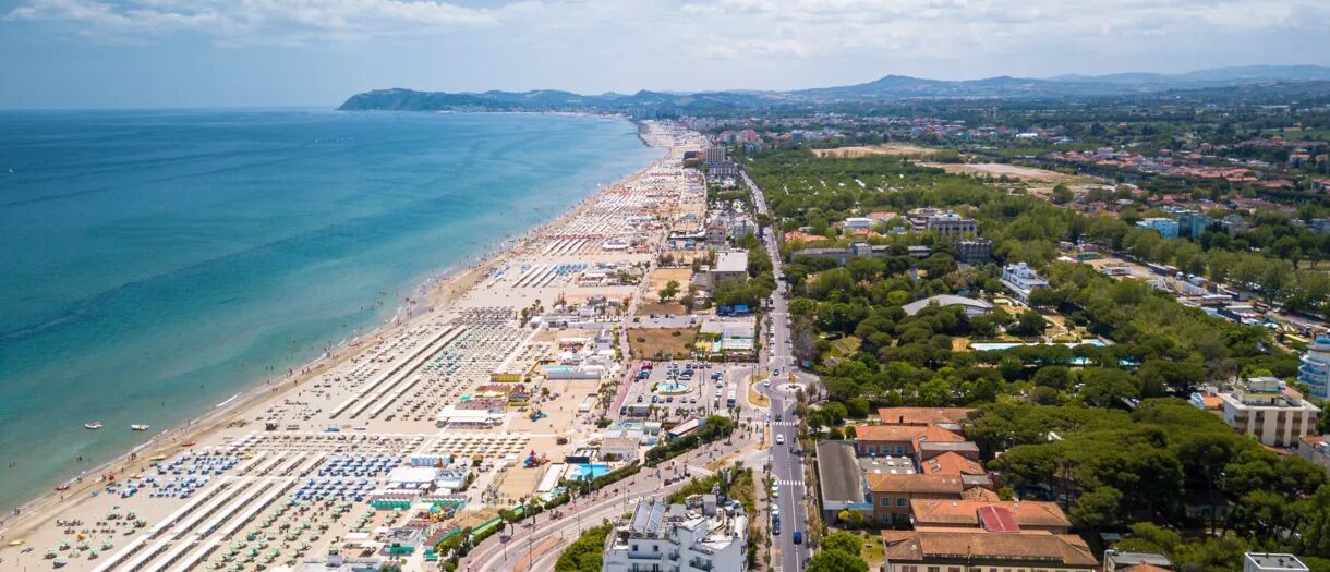 De lange stranden van Rimini aan de Adriatische kust met rijen parasols en de stad op de achtergrond.