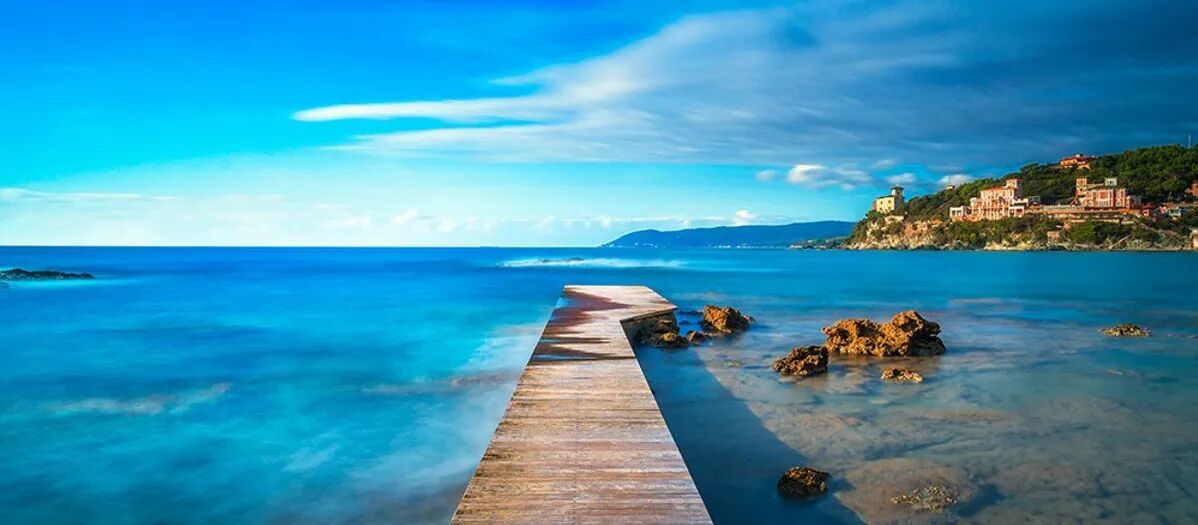 Een houten steiger aan een strand van het eiland Elba, met uitzicht over de heldere, turquoise zee.