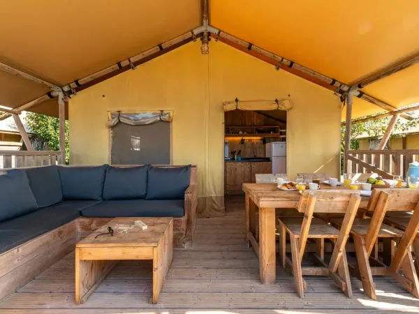 De Roan Lodgetent Luxe veranda beschikt over een tafel en stoelen.