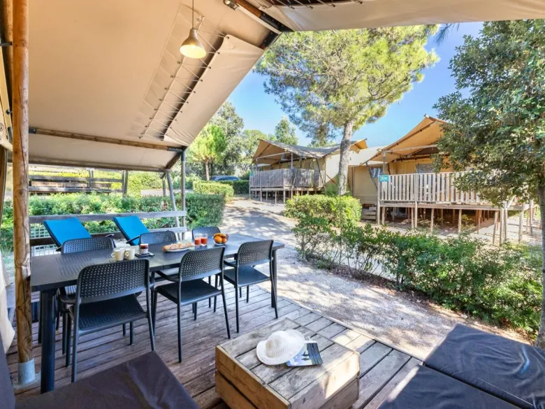 De Roan Lodgetent Premium beschikt over een ruim overdekte veranda met lounge hoek en eettafel.