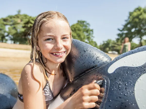 Meisje met opblaas speelgoed in natuurplas bij Roan camping De Schatberg.