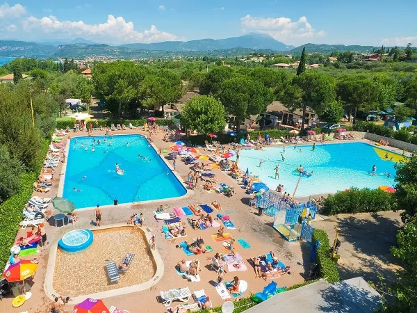 Overzicht zwembaden met ligbedden op Roan camping Cisano San Vito.