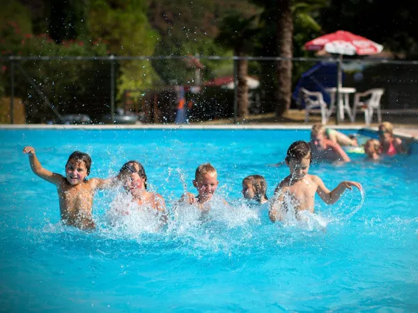 Kinderen hebben plezier in het zwembad op Roan camping La Rocca Manerba.