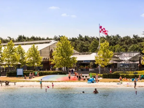 Overzicht van de waterplas met air trampoline bij Roan camping Terspegelt.