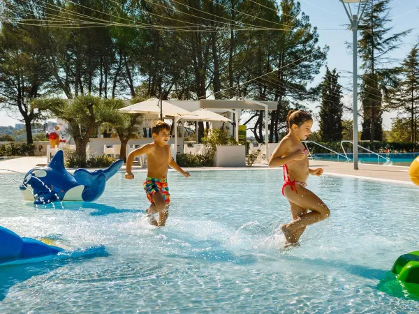 Rennende kinderen door het ondiepe zwembad op Roan camping Valkanela.