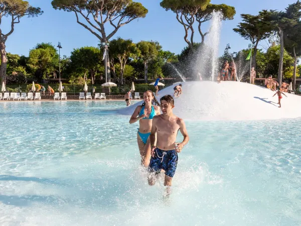 Kinderen rennen door het lagune zwembad op Roan camping hu Park Albatros village.