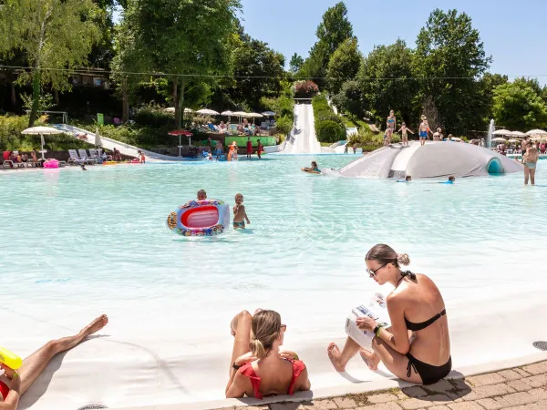 Ouders en kinderen genieten van lagune zwembad op Roan camping Altomincio.