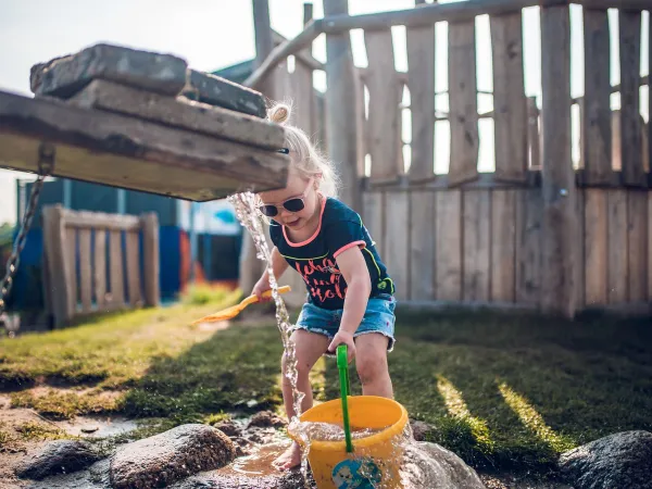 Spelend kind met water in de watervallei bij Roan camping Ackersate.