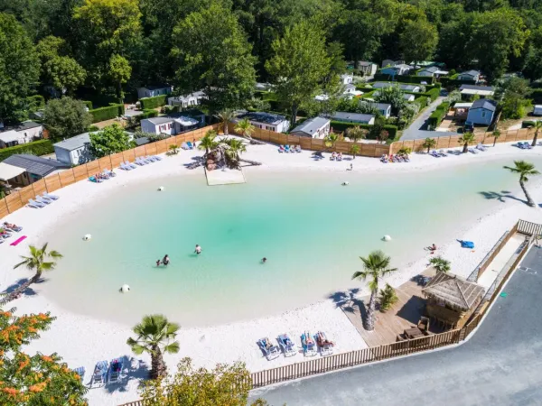 Overzicht van lagunebad met zandstrand op Roan camping La Clairière