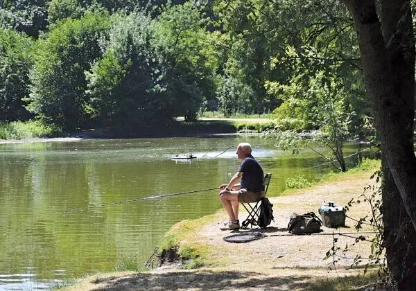 Man aan het vissen in de visvijver op Roan camping Domaine de la Brèche.