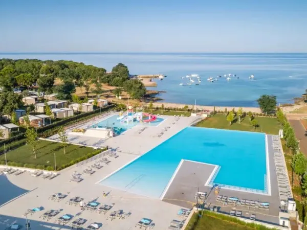 Zwembad met kinderbad en glijbaantjes en baai op Roan camping Park Umag.