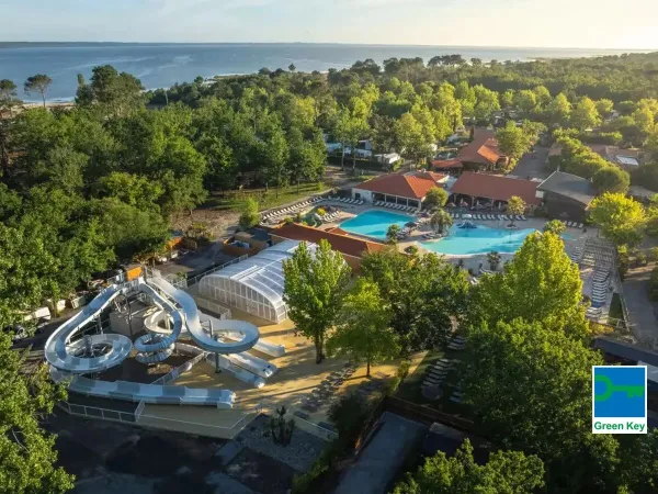Overzicht van zwembad met glijbaan en de zee in de verte op Roan camping Mayotte Vacances.