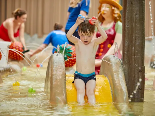 Jongetje beleeft waterpret van het glijbaantje in peuterbad op Roan camping Terspegelt.