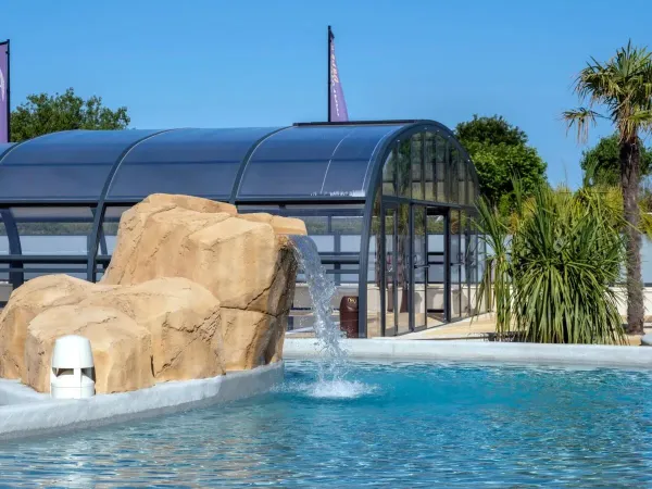 Overdekbaar zwembad en buitenzwembad met waterval op Roan camping Le Domaine du Clarys.