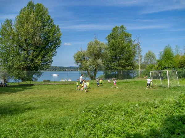 Kinderen voetballen op het voetbalveld op Roan camping Okay Lido.