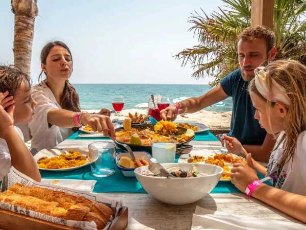 Een gezin zit te eten aan het strand op Roan camping Alannia Els Prats.