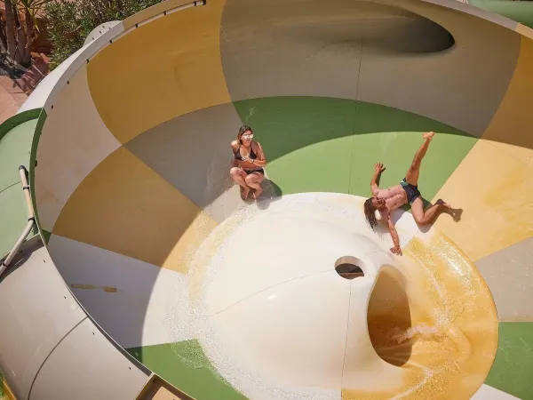 Twee mensen hebben veel plezier op de tornadoglijbaan op Roan camping Le Petit Mousse.