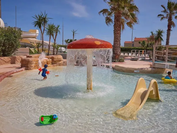 Kinderbad met glijbaantje en paddenstoelensproeier op Roan camping Le Petit Mousse.