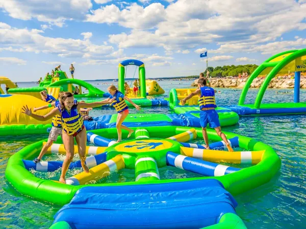 Kinderen spelen op luchtkussens in het meer op Roan camping Le Lac des Vieilles Forges.