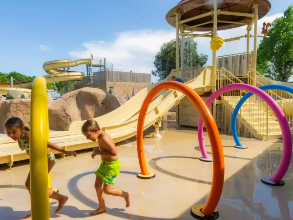 Kinderen rennen door de watersproeiers bij Roan camping Arinella Bianca.