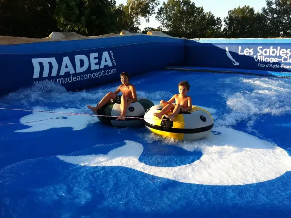 Kinderen aan het tubing op een kunstmatige golfsimulator op Roan camping Les Sables d'Or.