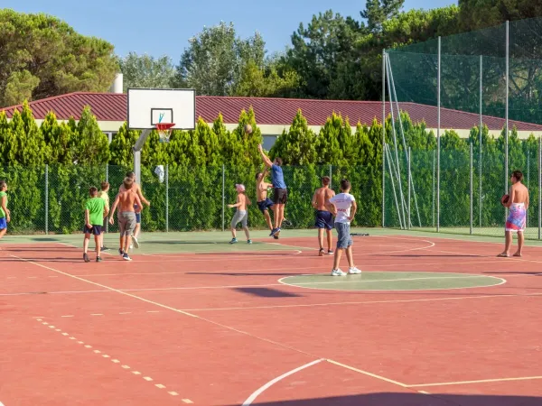 Kinderen spelen een wedstrijdje basketbal op het multisportterrein op Roan camping Marina Julia Camping Village.