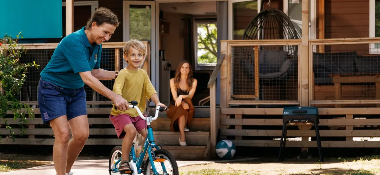 Roan campingmedewerkers en gasten met kinderfietsje.